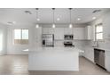 Bright kitchen with stainless steel appliances, white cabinets, a large island, and tile floors at 9042 N 116Th Ln, Youngtown, AZ 85363