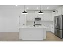 Modern kitchen with white cabinets, an island, stainless steel appliances, and sleek pendant lighting at 16610 N Dante Way, Maricopa, AZ 85138