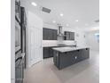 Open kitchen with an island, stainless steel hood, gray cabinets, and modern appliances, with ample lighting at 17626 W Oregon Ave, Litchfield Park, AZ 85340
