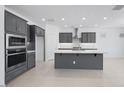 Modern kitchen featuring gray cabinets, stainless steel appliances, and a center island with a white countertop at 17626 W Oregon Ave, Litchfield Park, AZ 85340