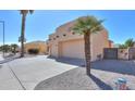 Beige stucco home with a two car garage, desert landscaping and palm trees at 923 W Crooked Stick Dr, Casa Grande, AZ 85122