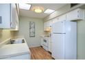 White kitchen with stainless steel appliances and wood flooring at 10076 W Lancaster Dr, Sun City, AZ 85351