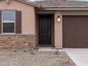 Close up of the front door entrance with stone veneer, brown shutters and garage door at 15995 W Cottontail Ln, Surprise, AZ 85387