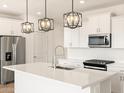 Modern kitchen with white cabinets, stainless steel appliances, a large center island, and stylish pendant lighting at 15995 W Cottontail Ln, Surprise, AZ 85387