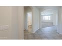 Hallway boasts tile flooring and leads to a bathroom and an arched opening to the living room at 43594 W Bravo Ct, Maricopa, AZ 85138