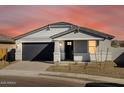 Well-lit exterior view of a gray single-story home with a dark garage door and tidy front yard at 16062 W Prickly Pear Trl, Surprise, AZ 85387