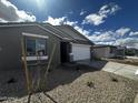 Single-Gathering home featuring a two-car garage, modern gray siding, desert landscaping and new tree at 4317 E Bradford Ave, San Tan Valley, AZ 85143