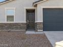 Dark brown front door with stone accents and landscaping at 9121 N 173Rd Ln, Waddell, AZ 85355