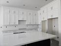 Bright kitchen showcasing white cabinetry, quartz countertops, and a sleek, dark island at 1907 W Brooke Ln, Queen Creek, AZ 85144