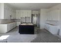 Spacious kitchen featuring white cabinetry, a center island, and tile flooring, awaiting final touches at 1907 W Brooke Ln, Queen Creek, AZ 85144