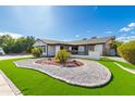 Inviting single-story home with a lush lawn, desert landscaping, and a charming exterior at 5038 W Echo Ln, Glendale, AZ 85302
