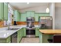 Bright kitchen featuring stainless steel appliances, green cabinetry, and island with bar seating at 45467 W Dirk St, Maricopa, AZ 85139