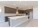 Modern kitchen with dark cabinets, quartz countertops, and stainless steel appliances at 266 S 165Th Ave, Goodyear, AZ 85338