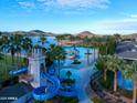 Aerial view of the community pool featuring a waterslide and a lake view backdrop at 8828 S 167Th Ln, Goodyear, AZ 85338