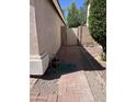 Side yard featuring a brick pathway leading to a gated entrance and a well-maintained wall at 12742 W Ash St, El Mirage, AZ 85335
