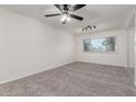 Bright, carpeted living room featuring a ceiling fan and a large window at 2608 W Berridge Ln # 220, Phoenix, AZ 85017