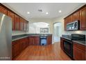 Well-lit kitchen boasts wood floors, dark wood cabinets, and stainless steel appliances at 27174 N 85Th Dr, Peoria, AZ 85383