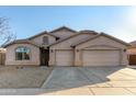 Tan three-car garage home with desert landscaping at 43205 W Askew Dr, Maricopa, AZ 85138