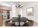 Cozy dining area with a round table and updated lighting fixture adjacent to the kitchen at 21067 N Sequoia Crest N Dr, Surprise, AZ 85387