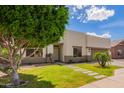 Modern home showcasing a lush lawn, desert plants, and a minimalist design with a light-colored exterior at 10101 E Posada Ave, Mesa, AZ 85212