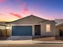 New home exterior at dusk showcasing a two-car garage at 9115 N 173Rd Ln, Waddell, AZ 85355