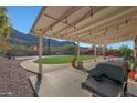 Covered patio, grassy lawn, and built-in grill in a backyard with mountain views at 2343 E Orangewood Ave, Phoenix, AZ 85020