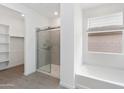 Well-lit bathroom featuring a glass shower, soaking tub, and ample natural light from a window at 36834 W La Paz St, Maricopa, AZ 85138