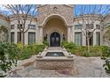 Charming home entrance with arched doorway, mature landscaping and a water feature for curb appeal at 6322 E Turquoise Ave, Paradise Valley, AZ 85253