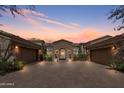 Beautiful stone home exterior with a three car garage and a well-manicured front yard under a colorful sunset at 6322 E Turquoise Ave, Paradise Valley, AZ 85253