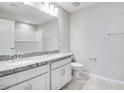 Bathroom features granite countertop with double sinks, white cabinets, tiled flooring, and a shower with tile surround at 8975 S 168Th Ln, Goodyear, AZ 85338