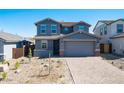 Two-story home featuring blue facade, gabled roof, with a brick driveway leading to an attached two-car garage at 8975 S 168Th Ln, Goodyear, AZ 85338