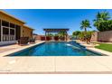 Relaxing pool view with a waterfall feature and shaded pergola seating area for outdoor entertaining at 18174 W Wind Song Ave, Goodyear, AZ 85338