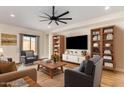 Inviting living room with wood floors, a ceiling fan, built-in shelving and comfortable seating arrangements at 18450 W Elwood St, Goodyear, AZ 85338