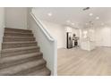 Open concept living space with stairway, wood-look floors, and a modern kitchen in the background at 2848 N Evergreen St, Buckeye, AZ 85396
