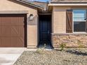 Close up of a home's entrance with a dark brown front door and stone veneer accents at 16032 W Desert Hollow Dr, Surprise, AZ 85387