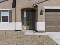 Close-up of a charming home's entrance with a dark front door and desert landscaping at 16072 W Prickly Pear Trl, Surprise, AZ 85387