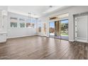 Spacious living room featuring hardwood floors, sliding doors and multiple windows that fill the room with natural light at 32962 N 131St Dr, Peoria, AZ 85383