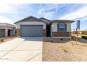 Charming single-Gathering home featuring stone accents, a gray garage door, and desert landscaping at 8584 N 170Th Ln, Waddell, AZ 85355