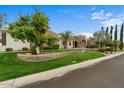 Exterior view of the house showcasing a beautiful lawn, mature trees, and unique architectural details at 2121 N Orchard --, Mesa, AZ 85213