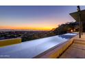 Infinity pool with city and mountain views at sunset at 4060 E Lamar Rd, Paradise Valley, AZ 85253