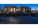 Stunning desert contemporary home with a stone facade and landscaped yard at twilight at 17213 E Morning Vista Ct, Rio Verde, AZ 85263