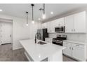 Modern kitchen with stainless steel appliances, white cabinetry, island sink, and elegant pendant lights at 17868 W Blue Sky Dr, Surprise, AZ 85387