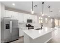 Stylish kitchen featuring stainless steel appliances, white cabinets and island, complemented by modern lighting at 17868 W Blue Sky Dr, Surprise, AZ 85387