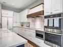 Bright kitchen with white cabinets, stainless steel appliances, and a wood range hood at 2749 E Pearl St, Mesa, AZ 85213