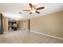Spacious living room with tile floors, ceiling fan, and views into kitchen at 41369 W Crane Dr, Maricopa, AZ 85138