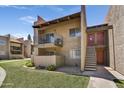 A tan stucco condo building showcases a balcony and nearby stairway, all surrounded by green grass and desert landscaping at 5525 E Thomas Rd # N1, Phoenix, AZ 85018