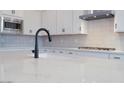 Close up view of the kitchen island with stone countertops, stainless appliances, and a black faucet at 3909 E Gold Mountain Ave, San Tan Valley, AZ 85143