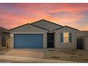 Beautiful gray home at sunset with a blue garage door, neutral exterior, and a neatly paved driveway at 8637 W Warner St, Tolleson, AZ 85353