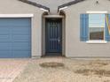 Close-up of home's gray exterior with a blue garage door, and a neatly paved driveway at 8637 W Warner St, Tolleson, AZ 85353