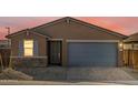 A view of the front of the home, which features a two-car garage and desert landscaping at 8657 W Warner St, Tolleson, AZ 85353